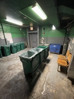 Overflowing trash bins spilling bags across the compactor room floor